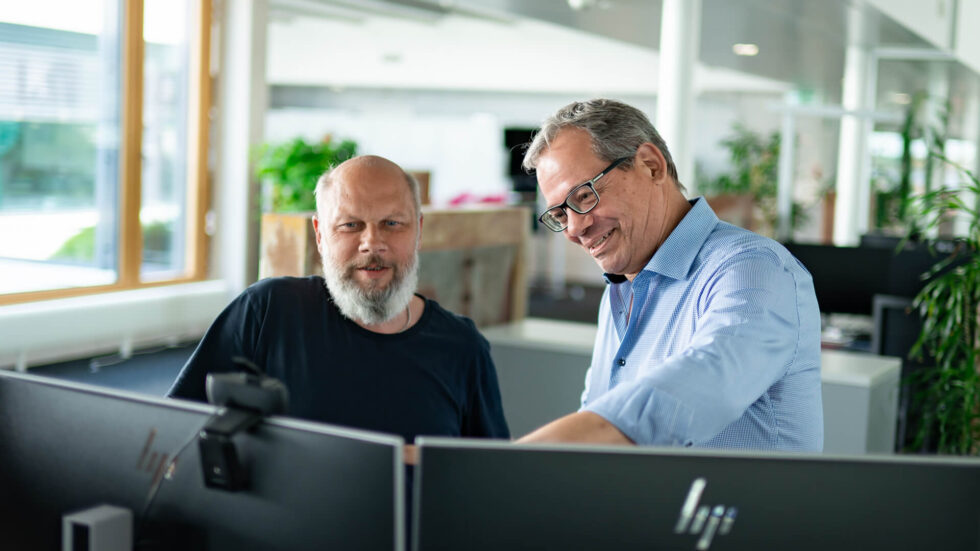 Zwei Mitarbeiter vor dem Laptop am arbeiten